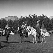Cover image of [People dressed in regalia standing next to tipi and people dressed in regalia on horses]