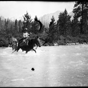 Cover image of [Lois Barnes?] fording river on horseback