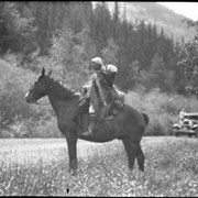 Cover image of Unknown woman with baby on her back riding horse