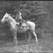 Cover image of Unknown child in regalia on horse, part of the Rider family
