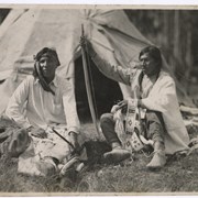 Cover image of Two unidentified men sitting in front of a tepee