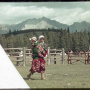 Cover image of Woman with baby walking past a tepee