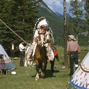 Cover image of Man in regalia on horseback between tepees